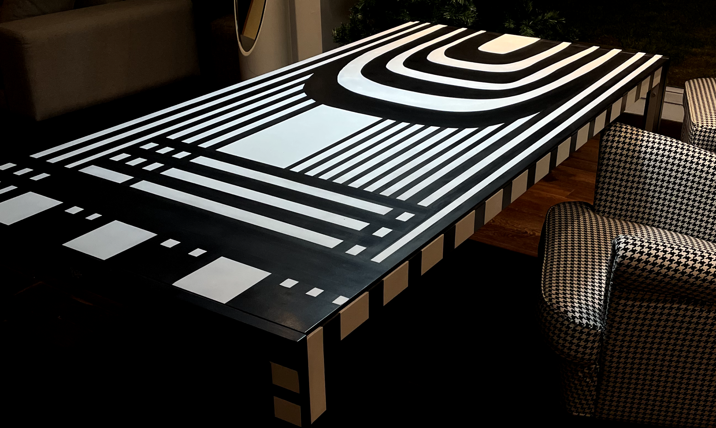 Black table with a bold white geometric design resembling a road or circuit pattern, composed of stripes, curves, and rectangles.
