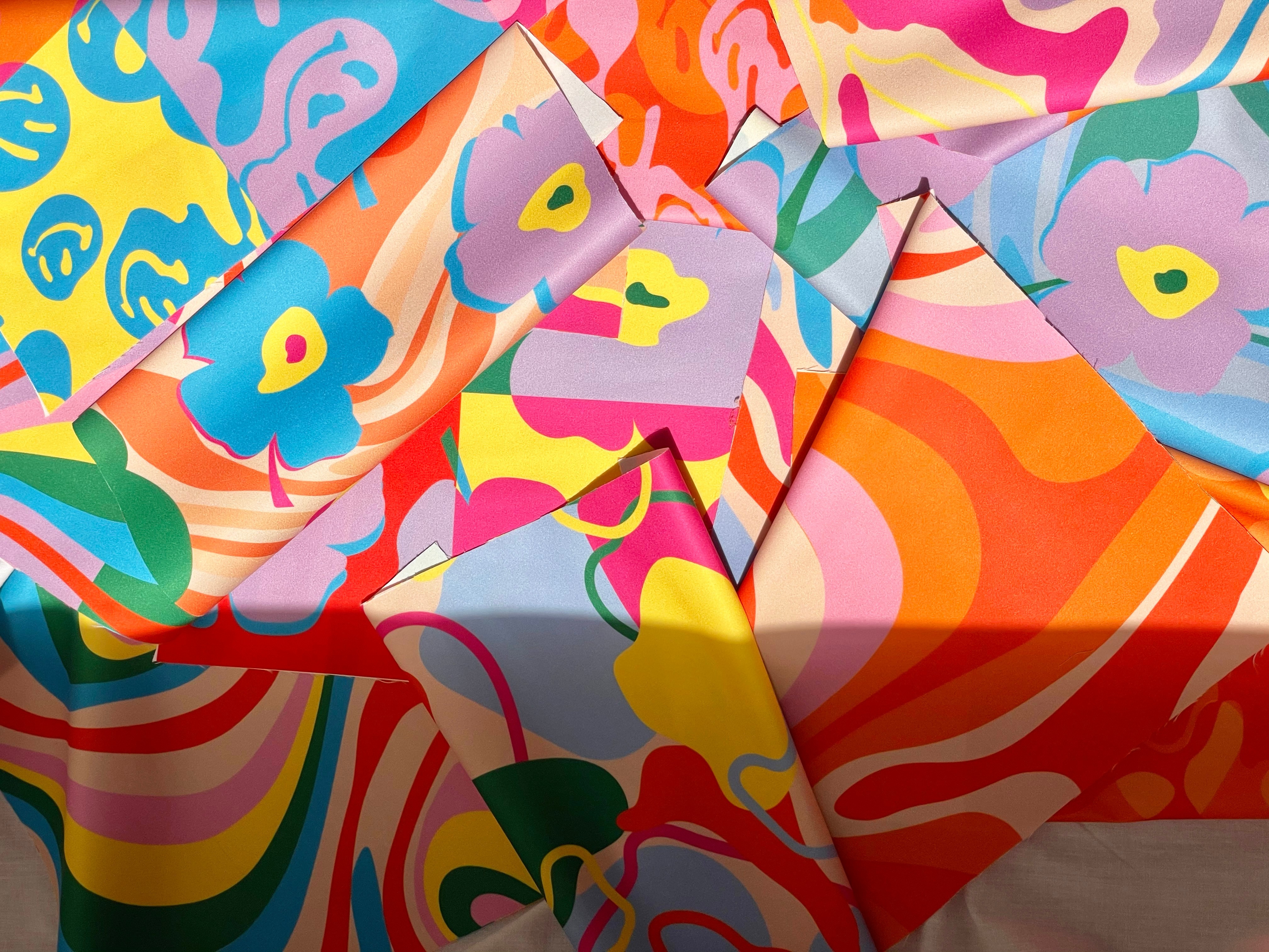 Close-up of a vibrant, multicolored fabric with swirling abstract patterns in orange, pink, yellow, blue, and green tones.