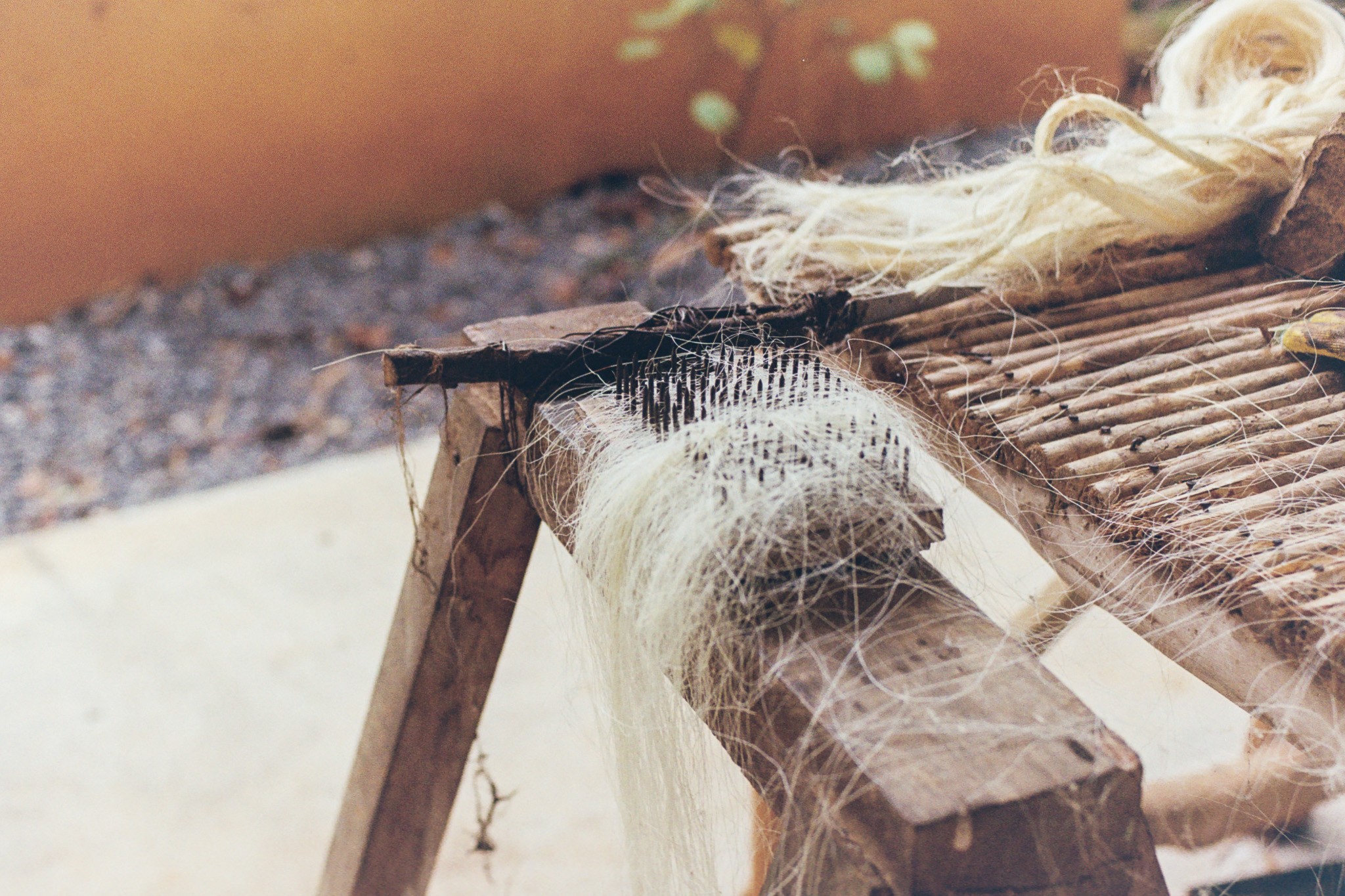 Image of a close-up of threads stretched across wooden beams in natural light.